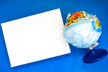 Metinleriniz için ışık kutusu, mavi arka planda tıbbi yüz maskesi, karantina ve virüs ilacı konsepti, seyahat ve koronavirüs konsepti olan dünya dünyasını kopyalayın