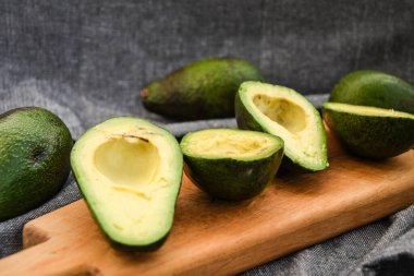 Taze avokado, olgun avokado ve avokadoyu kemikle keser. Tahta bir sandıkta olgun sonbahar armutları