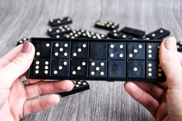 Playing dominoes on a wooden table. Woman\'s hand with domino. Leisure games concept. Selective focus. Table game girl playing
