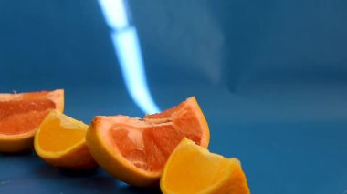 Dilimlenmiş turunçgil, greyfurt ve turuncu mavi arka planda, güneş ışığı, doğal vitaminler, sağlıklı beslenme