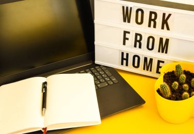 Not defteri, dizüstü bilgisayar ve kalem, kaktüs, evden çalışma, sarı arkaplan fotokopi alanı üzerinde serbest çalışma ortamı, planlama günü, liste yapma