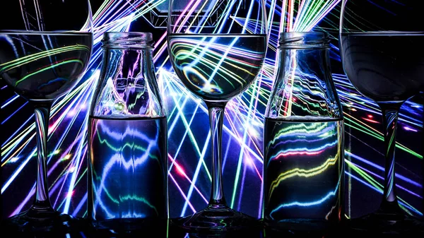 luxury splash drink in a glass on a high leg on a colored background with dark light behind, a bar rack in restaurant.