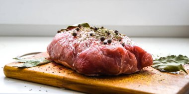 Çiğ domuz omuzu ve baharat. Koyu yaprak, ahşap arka planda, kapak, baharatlı taze çiğ et, fileto, kürek, boyun, arka bacak bifteği üzerine siyah biber