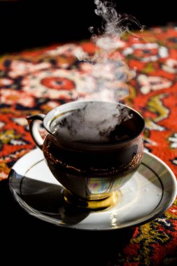 Türkçe halıda klasik porselen çay saati, porselen fincanda siyah çay güneş ışığında çay tabağı, Asya çay seremonisi, sıcak buhar.