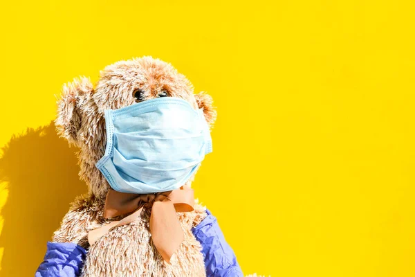 Coronavirus covid-19 and pollution protection concept. teddy bear doll wearing mask and protective gloves to against corona virus and air pollution pm2.5 isolated on yellow background, copy space