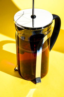 Bitkilerle demlenmiş baharatlı meyve çayı, gül çiçekleri, sarı arkaplanda metin için fotokopi alanı olan sıcak sağlıklı içecek, Hibiscus çayı, çiçek ve kuru çiçek, sıcak çay ile cam çaydanlık.