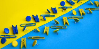 Ofis malzemeleri renkli düğmeler ve ataçlar şeklinde, sarı ve mavi arkaplanda mandallar, kopya alanı, sınır ve çerçeve, okul konseptine geri dönüş