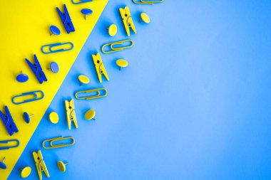 Ofis malzemeleri renkli düğmeler ve ataçlar şeklinde, sarı ve mavi arkaplanda mandallar, kopya alanı, sınır ve çerçeve, okul konseptine geri dönüş