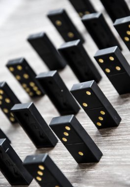 Açık tahta bir masa üzerindeki siyah dominolar art arda dururlar, seçici odak, eski siyah, karton arka planda klasik dominolar. Oyun dominoları konsepti