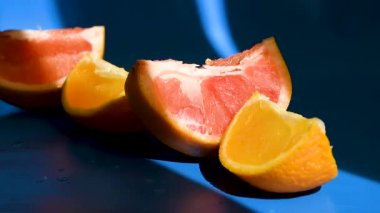 Dilimlenmiş turunçgil, greyfurt ve turuncu mavi arka planda, güneş ışığı, doğal vitaminler, sağlıklı beslenme