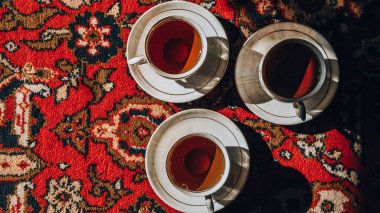 Türkçe halı üzerinde çay tabakları olan klasik Sovyet porselen bardakları, geleneksel çay seremonisi, güneş ışığı.