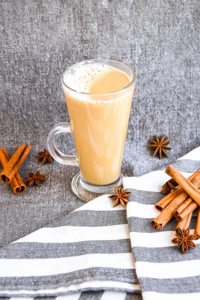 Traditionele wintereierpunch in glazen mok met melk, kaneel en anijs sterren bedekt met slagroom op een grijze doek, — Stockfoto