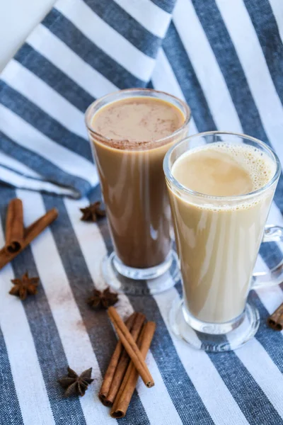 Iced coffee with milk in tall glasses, Cups of tasty frappe coffee, Latte machiato, two cups of cappuccino with cinnamon sticks and anise stars