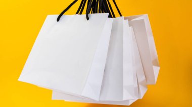 Sarı arka planda alışveriş yapmak için beyaz kese kağıdı seti. Düz metin veya ürün için tasarım, kopyalama alanı, alışveriş poşeti ve kopyalama alanı