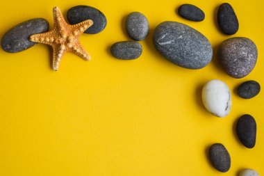 Deniz kabuğundan çerçeve, yıldız ve taşlar, yaz konsepti, sarı arka planda kopyalama alanı, tatil, tatil