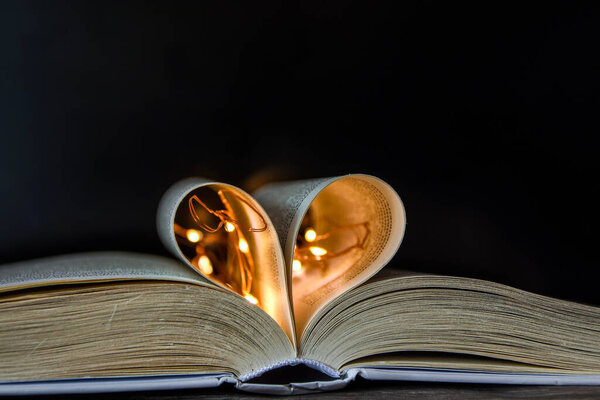 Book with love symbol isolated on black background, Love books, love to read, love stories, heart shape from paper book, Romantic background with the book