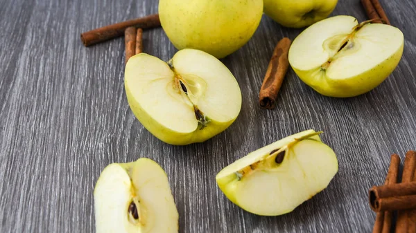 green golden apples or Granny smith with cinnamon sticks on wooden background, preparing food, dessert, healthy nutrition, autumn time