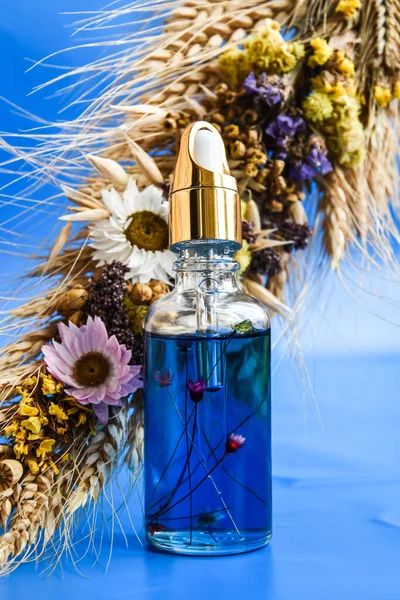 Aging Serum Glazen Fles Met Druppelaar Blauwe Achtergrond Droge Bloemen — Stockfoto