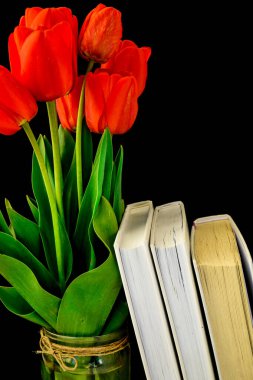 Kapalı kırmızı laleler çiçek demeti içinde yapraklar siyah arkaplanda izole kitaplar, metin için boşluk kopyala