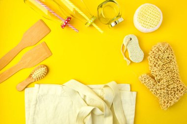 Sıfır atık. Tekstil eko torbaları, cam kavanozlar, ahşap saç fırçası ve sarı arka planda fotokopi uzayı olan el bezi. Çevre dostu ve konsepti yeniden kullan. Üst görünüm veya düz uzanma