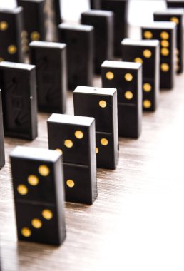 Açık tahta bir masa üzerindeki siyah dominolar art arda dururlar, seçici odak, eski siyah, karton arka planda klasik dominolar. Oyun dominoları konsepti