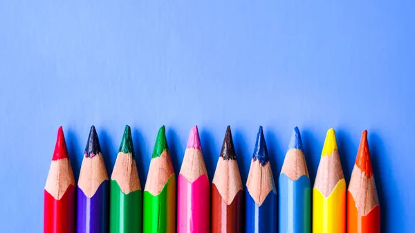 Crayons Colored pencils background. Color pencils on blue background. Close up. Copy space, top view of colorful various pencils placed in row