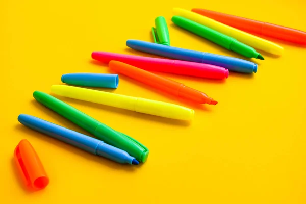 コピースペースのある黄色の背景にフェルト先端のペン キャップの近くに新しい明るいプラスチック製のオープンカラーフェルトペンのセット 事務用品の概念 — ストック写真