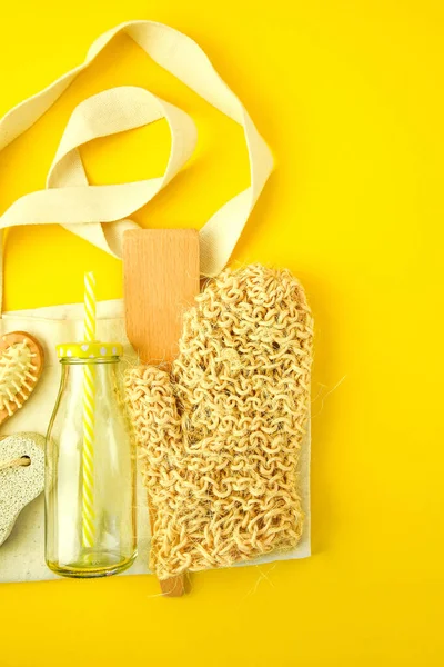 Zero waste concept. Textile eco bags, glass jars, wooden hair brush and washcloth on yellow background with Copy space. Eco friendly and reuse concept. Top view or flat lay