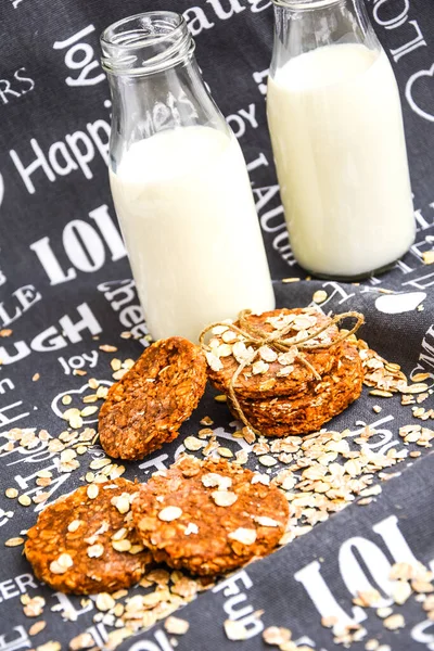 Oat and peanut butter cookies, close up with bottles of milk, homemade oatmeal cookies with chocolate and banana with almond