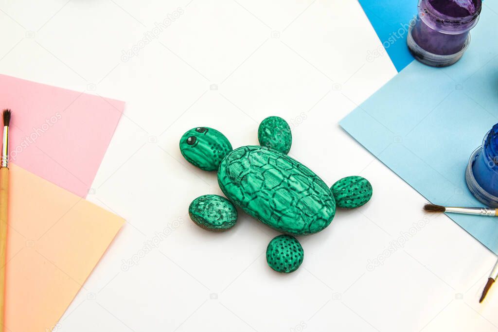 Painting a rock green turtle on a stone step by step. Children art project. DIY concept. Step by step photo instruction.View from above. Work with children and adults in quarantine.