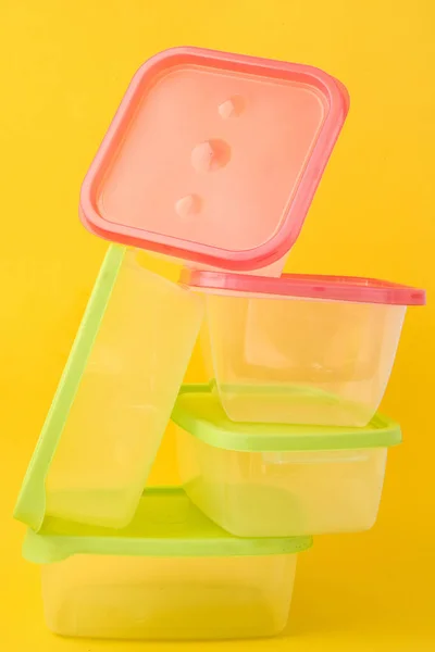 Plastic lunch boxes on yellow background, Colorful Plastic Containers, empty plastic food containers with colorful lids