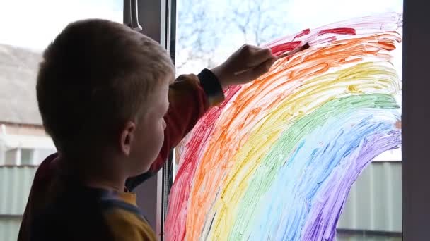 Niño pintando arco iris en la ventana durante la cuarentena Covid-19 en casa. Quédate en casa campaña de medios sociales para la prevención del coronavirus, vamos a estar todos bien — Vídeo de stock