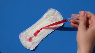 Bir kız regl pedine kan döker gibi kırmızı su döküyor. Sızıntı koruma kavramı