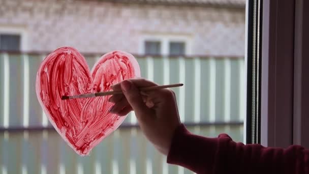 Quarantaine. Vrouwelijke hand trekt rood hart op het raam met verf. Wachten op de regenboog, thuisblijven — Stockvideo