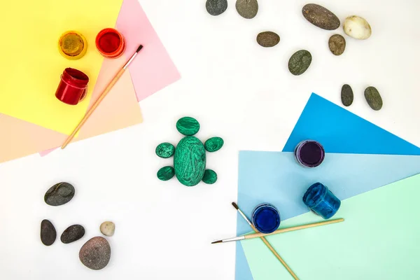 Painting a rock green turtle on a stone step by step. Children art project. DIY concept. Step by step 3 photo instruction.View from above. Work with children and adults in quarantine.