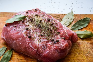 Çiğ domuz omuzu ve baharat. Koyu yaprak, ahşap arka planda, kapak, baharatlı taze çiğ et, fileto, kürek, boyun, arka bacak bifteği üzerine siyah biber