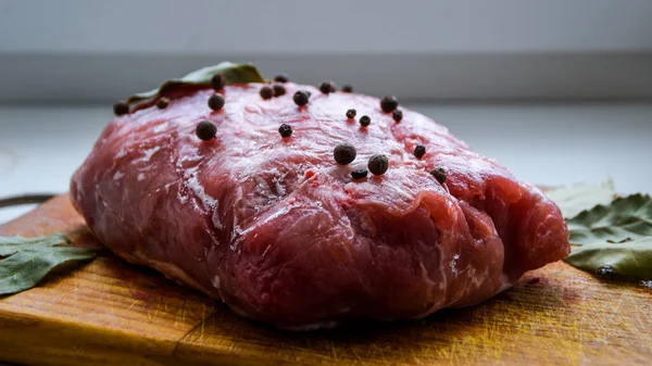 Çiğ domuz omuzu ve baharat. Koyu yaprak, ahşap arka planda, kapak, baharatlı taze çiğ et, fileto, kürek, boyun, arka bacak bifteği üzerine siyah biber