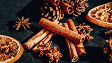 Kuru portakal dilimleri, tarçın ve yıldız anasonlarının arka planı, hazırlanmak için malzemeler, siyah arka planda sıcak şarap, Noel baharatları.