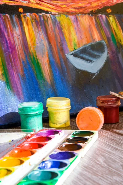 Tempera paints on the table in a workshop, selective focus, Set of watercolor paints, brushes for painting and palette on old vintage wooden background