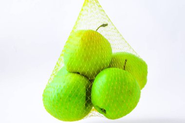 Beyaz bir duvarın önünde portakal ağıyla asılı bir grup elma. Trend. Diyet ve sağlıklı yemek kavramı, metin yeşili Granny Smith ve altın sarısı için kopyalama alanı