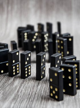 Açık tahta bir masa üzerindeki siyah dominolar art arda dururlar, seçici odak, eski siyah, karton arka planda klasik dominolar. Oyun dominoları konsepti