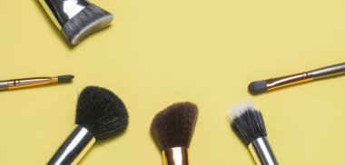 Brochas para maquillaje acomodadas de forma estetica con un fondo amarillo