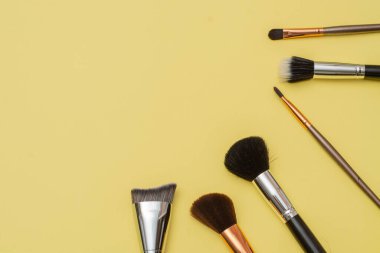 Brochas para maquillaje acomodadas de forma estetica con un fondo amarillo