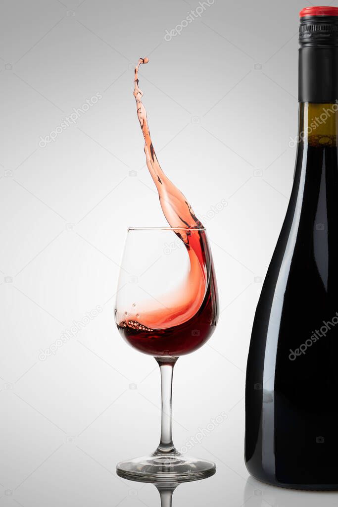 Botella de Vino con fondo blanco y una copa de vino con splash o vino en movimiento