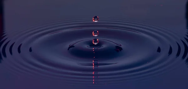 Сине Фиолетовые Капли Воды Взвешенные Воздухе Образующие Рябь Жидкой Поверхности — стоковое фото