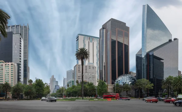 Mexico City 'nin binaları Avenida Reforma' nın kavşağında. Mavi gökyüzü ve yarı boş sokakları var.