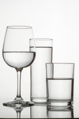 Beyaz arka plan ve yüzeyinde su olan bardak ve bardaklar.