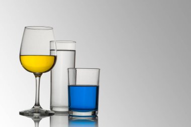 Beyaz arkaplanı olan bardak ve kristal bardaklar ve değişik renk ve tiplerde içecekler, çekici kompozisyonlar.