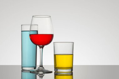 Beyaz arkaplanı olan bardak ve kristal bardaklar ve değişik renk ve tiplerde içecekler, çekici kompozisyonlar.