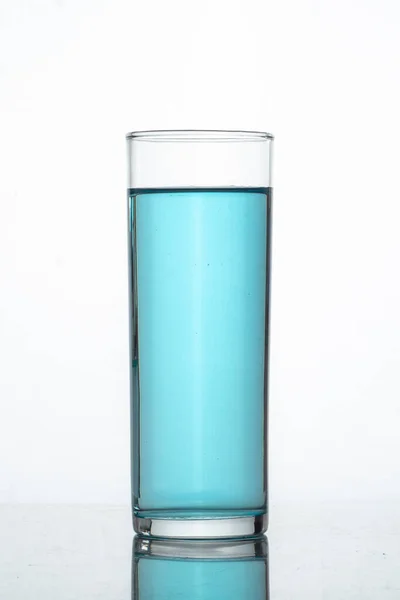 Mavi sıvı veya içecek içeren cam bardak ve beyaz arkaplan